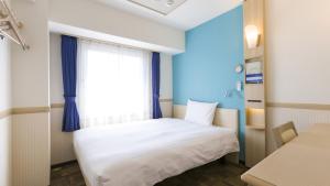 a bedroom with a white bed and a window at Toyoko Inn Shizuoka eki Kita guchi in Shizuoka