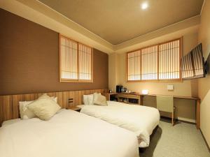 a room with two beds and a desk and two windows at HOTEL CUORE Kyoto Shijo Omiya in Kyoto