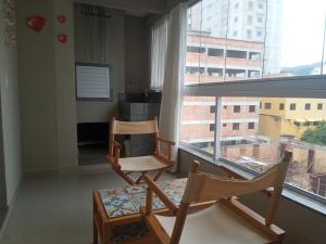 2 sillas en una habitación con ventana grande en Aconchegante apartamento em Itapema 300 mts praia, en Itapema