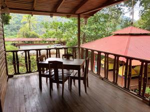 a wooden porch with a table and chairs on a deck at Esquipulas Rainforest in Quepos