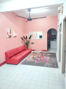 a living room with a red couch and pink walls at Yoni Homestay in Kampung Raja