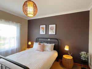 a bedroom with a bed with two tables and two lamps at Stunning Hobart 3-bed home- close to shopping centers in Glenorchy +18 photos