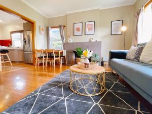 een woonkamer met een blauwe bank en een tafel bij Stunning Hobart 3-bed home- close to shopping centers in Glenorchy