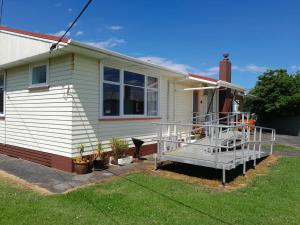 a white house with a porch with plants on it at Ironsands Cottage in Patea