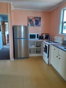 a kitchen with a stainless steel refrigerator and a microwave at Ironsands Cottage in Patea