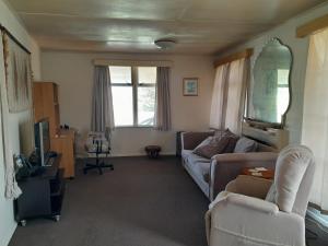 a living room with a couch and a tv at Ironsands Cottage in Patea