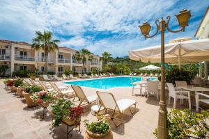 een uitzicht op het zwembad van het resort met stoelen en een parasol bij Edelweiss Hotel in Argassi