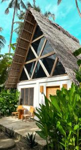 een huis met een rieten dak en een tafel en stoelen bij Bermuda Triangle Bungalows in Siquijor