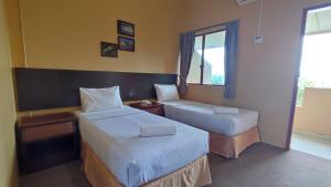 a hotel room with two beds and a window at Mersing Merlin Inn in Mersing