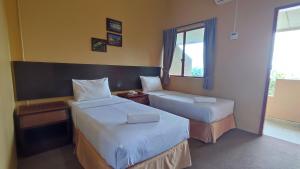 um quarto de hotel com duas camas e uma janela em Mersing Merlin Inn em Mersing