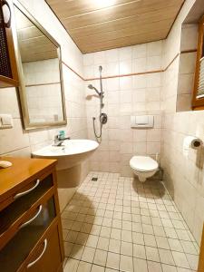 un bagno con lavandino, WC e specchio di Herzensort - Schönes Haus mit Terrasse und Gartenblick a Rödermark