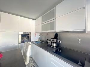 een keuken met witte kasten en een zwart aanrecht bij Studio Saintes-Maries-de-la-Mer, 1 pièce, 3 personnes - FR-1-475-99 in Saintes-Maries-de-la-Mer