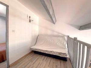 - un petit lit dans une chambre avec une croix sur le mur dans l'établissement Appartement Saintes-Maries-de-la-Mer, 3 pièces, 4 personnes - FR-1-475-83, à Saintes-Maries-de-la-Mer