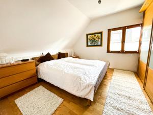 una camera da letto con un letto, un comò e una finestra di Herzensort - Schönes Haus mit Terrasse und Gartenblick a Rödermark