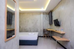een kleine kamer met een bed en een bureau bij Urbanview Hotel Syariah Artamara Tegal by RedDoorz in Tegal