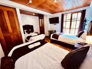 Habitación de hotel con 3 camas y TV en SAYACMARCA CLASSIC Inn, en Machu Picchu