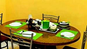 a wooden table with green napkins and plates on it at D'Serina Homestay-3 bedroom 6 bed & free parking in Sungai Petani +20 photos