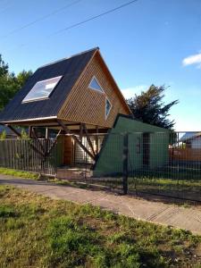 a house with a black roof and a fence at EL RINCON DE LÚ in Chile Chico