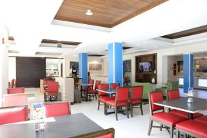 a dining room with tables and red chairs at Holiday Inn Express Hotel & Suites Albuquerque Airport, an IHG Hotel in Albuquerque