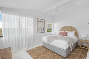 a white bedroom with a bed and a window at Walters in East Ballina