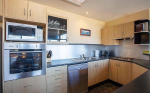 a kitchen with stainless steel appliances and wooden cabinets at Dromaius 6 in Jindabyne
