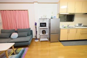 a living room with a couch and a kitchen at Guest House Kubo Homes Matsu in Osaka