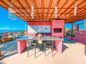 a pink kitchen with a table and chairs on a deck at Vila Real Apartamentos in Itacaré