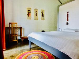 1 dormitorio con 1 cama blanca y 3 cuadros en la pared en Le Chat'o Park Hotel Ivato Airport NAVETTE GRATUITE H24 en Antananarivo