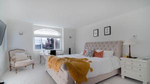 una camera da letto bianca con un letto grande e una sedia di 温西区豪华别墅附有按摩浴缸钢琴，接近机场downtown a Vancouver