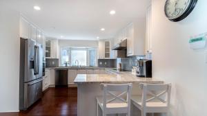 a kitchen with white cabinets and a counter with stools at 温西区豪华别墅附有按摩浴缸钢琴，接近机场downtown in Vancouver