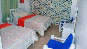 Un pequeño dormitorio con 2 camas y una silla azul en D´ Yoko Village´s, en Pedernales