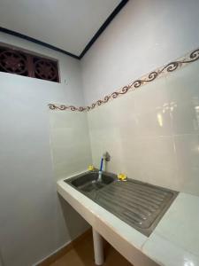 a bathroom with a sink in a white wall at Guest House Pondok Puspa Ayu in Kuta
