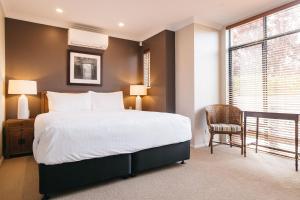 a bedroom with a large bed and a chair at Banksia by the Bay in Emu Point