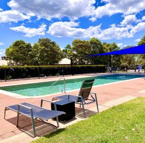a table and a chair next to a swimming pool at Beautiful Villa in the heart of the Hunter Valley in Pokolbin
