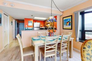 a dining room and kitchen with orange walls and a table and chairs at Sea Watch 1110 in Ocean City