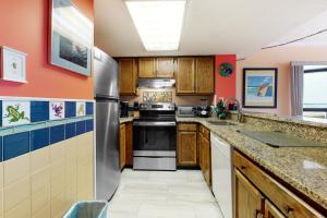 大洋城的住宿－Sea Watch 1110，厨房配有木制橱柜和不锈钢冰箱。