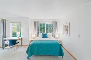 a white bedroom with a blue bed and a desk at Cannon beach vibes, steps to the beach,WIFI,3 full bedroom en suites with 3 fireplaces,Near Downtown in Cannon Beach
