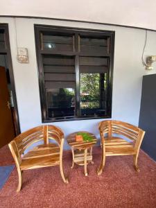 two chairs and a table in a room with a window at Guest House Pondok Puspa Ayu in Kuta