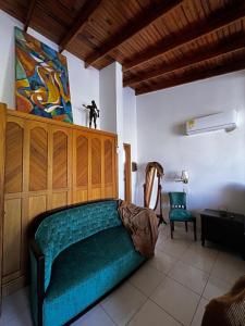 サン・アンドレスにあるSunset Paradiseの緑のソファ付きのベッドルーム1室、壁に絵画が飾られています。