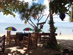 een tafel op het strand met stoelen en parasols bij Andaman Bay Bungalow in Koh Lanta