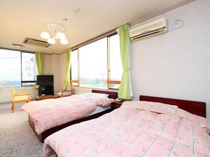 a bedroom with two beds and a tv and windows at Seaside Hotel Kujukuri in Sanmu