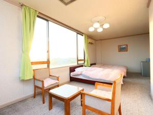 a bedroom with a bed and two chairs and a window at Seaside Hotel Kujukuri in Sanmu