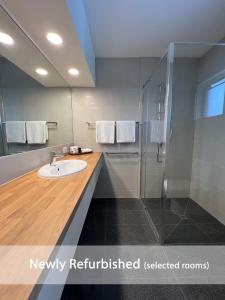 uma casa de banho com um lavatório e um chuveiro em Summerhill Motor Inn em Merimbula
