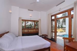 a bedroom with a bed and a large window at Paraikal Beach Resort in Kolachel