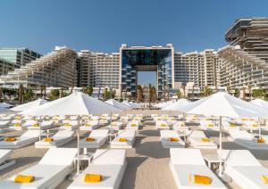 a beach with white lounge chairs in front of a city at Five Palm Residences in Dubai