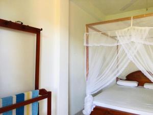 Schlafzimmer mit Himmelbett und weißen Vorhängen in der Unterkunft Sudumal Cottage in Ella