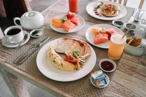 a table topped with plates of food and drinks at Bukal Sari Villas Uluwatu in Uluwatu