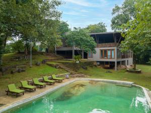 uma casa com uma piscina com cadeiras e uma casa em Birds Park Polgahawela em Egalla