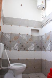 a bathroom with a toilet and a tiled wall at Dwaraka Guest House in Tiruvannāmalai