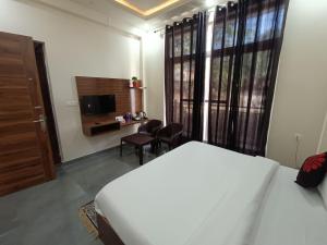 a bedroom with a bed and a desk and a television at Blessings Always Homestay in Dehradun